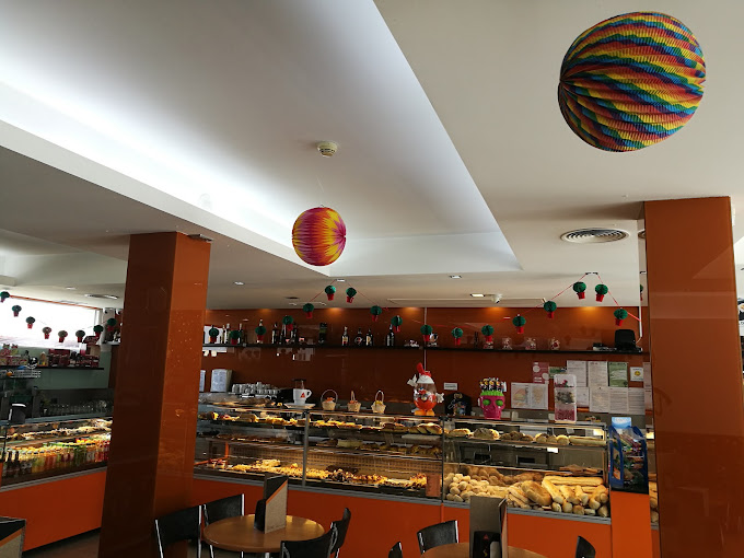 Interior da pastelaria, com o balcão e os balões de papel coloridos